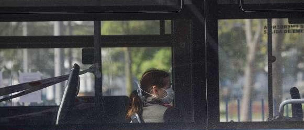 Una mujer con mascarilla, en un autobús.