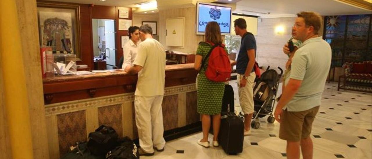 Turistas esperan a ser atendidos en la recepción de un hotel.