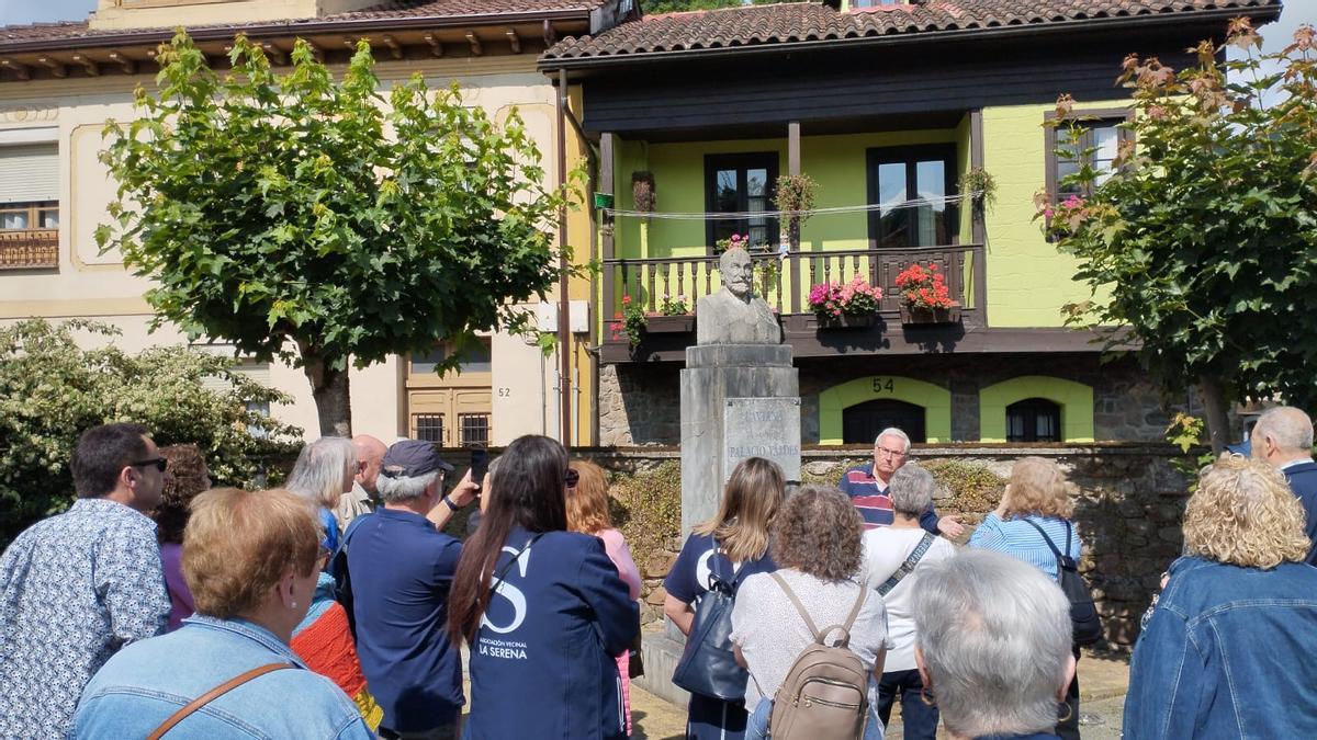 Francisco Trinidad, al fondo, ante el busto de Palacio Valdés en Entralgo, Laviana, ofrece explicaciones a los miembros de la Asociación de Vecinos &quot;La Serena&quot;, de Gijón