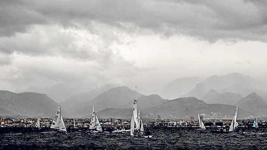 La flota navega bajo un intenso nubarrón en la bahía.