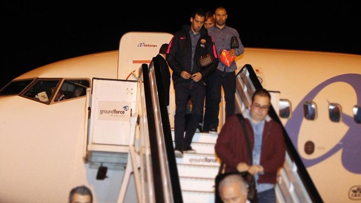 Busquets, delante de Mascherano, desciende del avión.