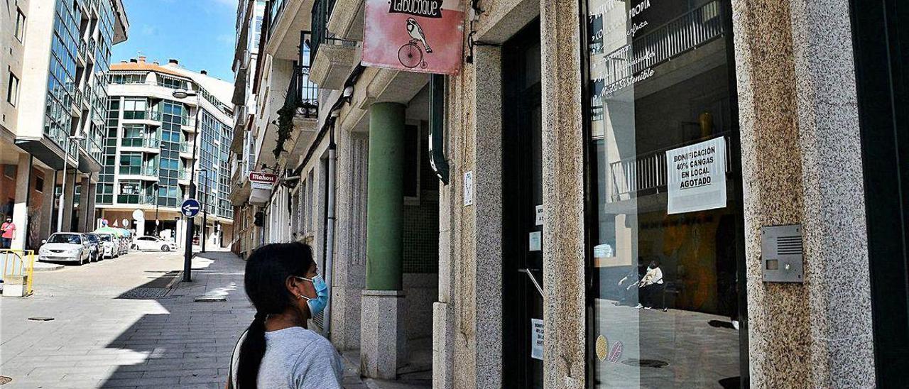 Una mujer observa el escaparate de un comercio de Cangas con el cartel de &quot;bono agotado&quot;.