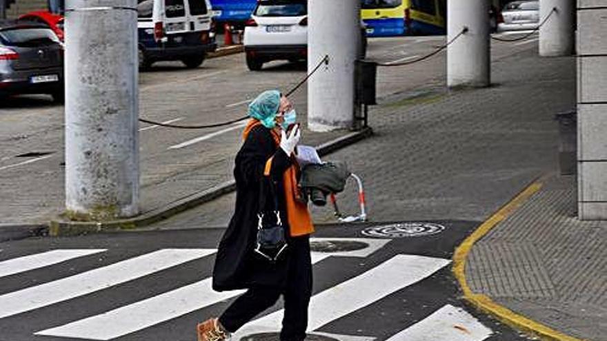 Una mujer con mascarilla, guantes y protector de pelo, ayer, en el entorno del Hospital de A Coruña.