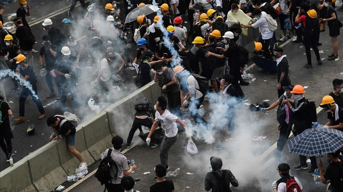 Un manifestante devuelve un gas lacrimógeno durante los enfrentamientos con la policía fuera de la sede del gobierno en Hong Kong. La policía trató de detener a los manifestantes que asaltan el parlamento de la ciudad mientras decenas de miles personas bloquearon arterias clave en una demostración de fuerza contra los planes del gobierno de permitir la extradición a China