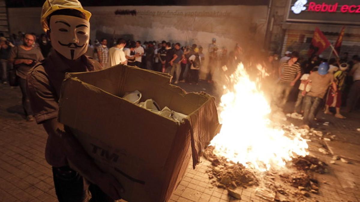 Un manifestante acarrera una caja con mascarillas cerca de una barricada en Estambul.
