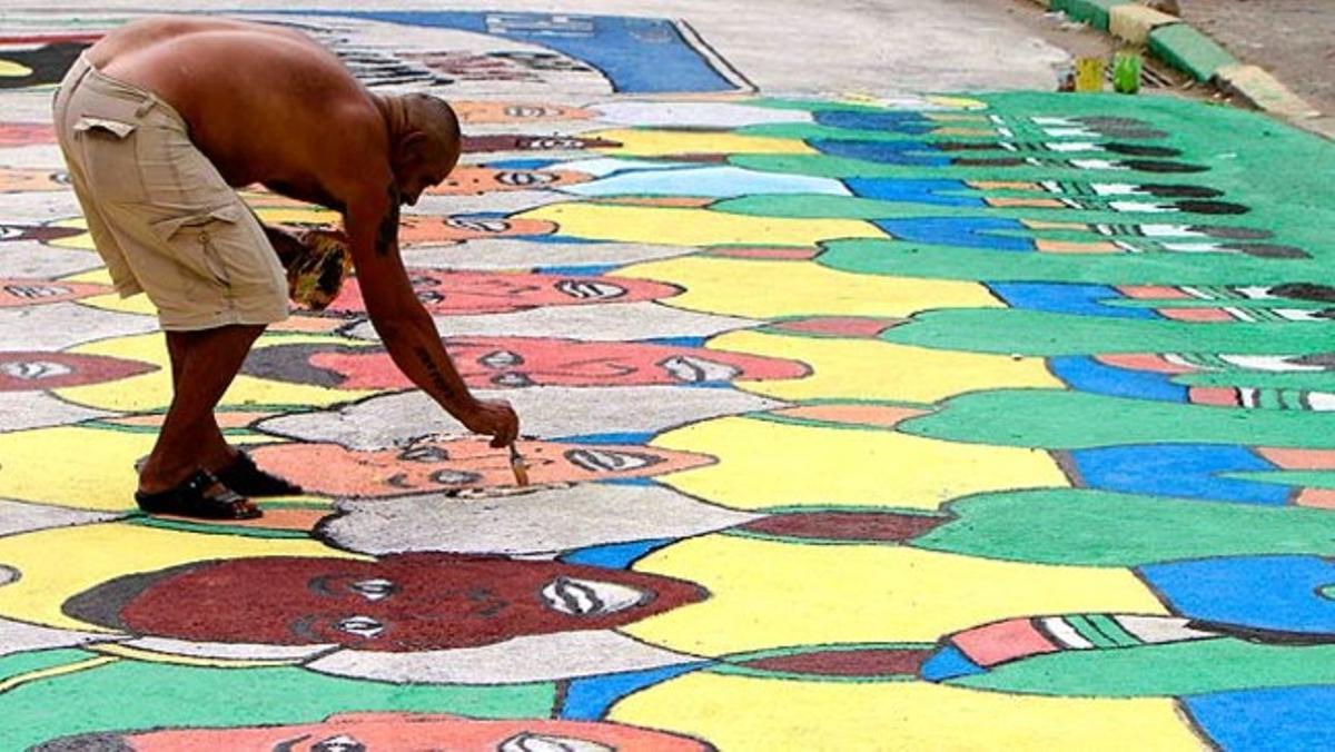 Un home dibuixa l’equip de futbol del Brasil sobre un carrer de Rio de Janeiro.