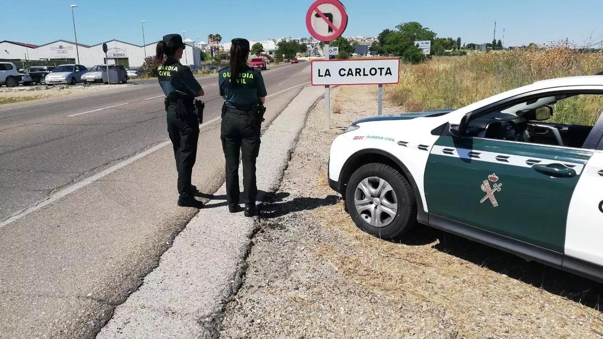 Dos agentes de la Guardia Civil, a la entrada de La Carlota.