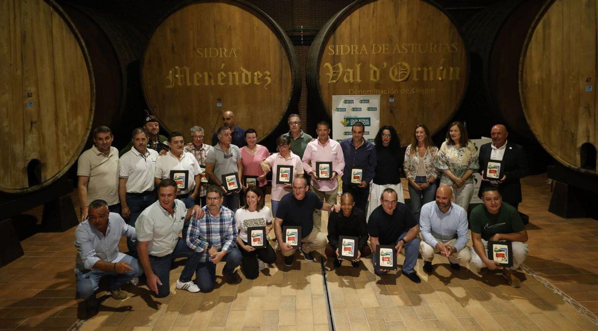 Los homenajeados escancian sidra y siguen los consejos ofrecidos en el decálogo de Tino Ovín: elevar mucho el brazo, sujetar el vaso desde el centro y acercar la botella. | LUISMA MURIAS