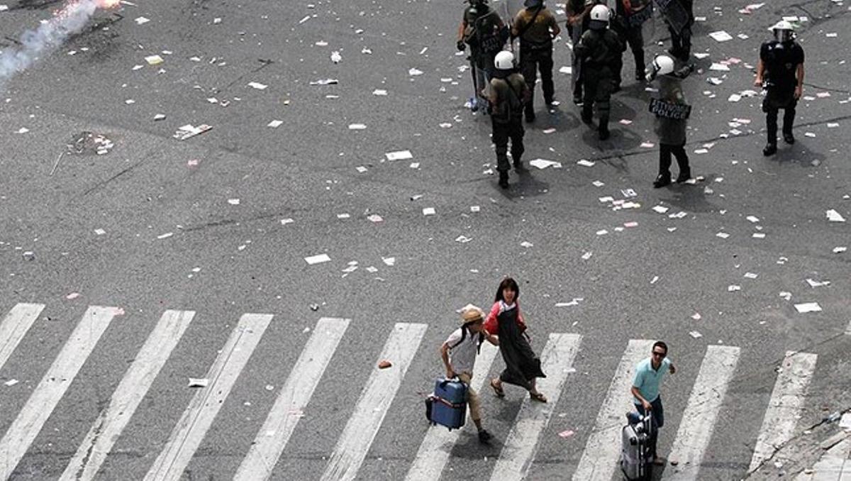 Uns turistes corren espantats aquest dimecres pels carrers d’Atenes mentre es produeixen enfrontaments entre la Policia grega i els manifestants, el mateix dia que al país es fa una vaga general per protesta contra les mesures d’austeritat empreses pel Govern.