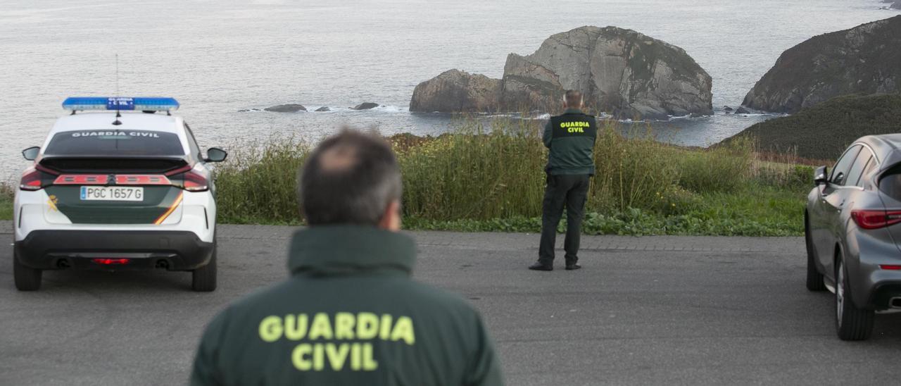 Dos agentes de la Guardia Civil, en el entorno de la peña de El Castro, próxima al Cabo Peñas, al fondo.