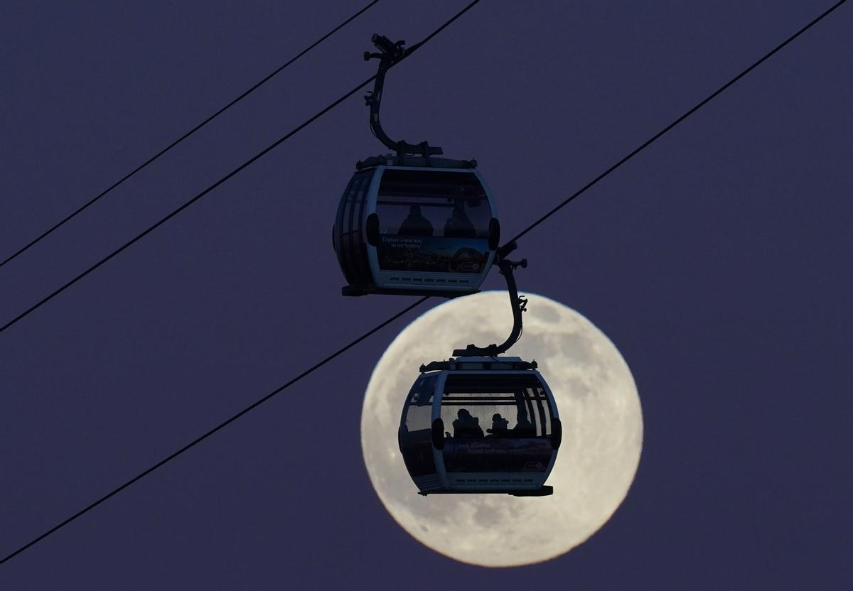 Los teleféricos pasan sobre el río Támesis, mientras nace la luna llena momento en que la luz se refleja en toda la cara de la Luna.