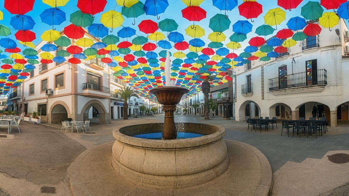 Miles de paraguas dan sombra en la plaza Mayor de Malpartida de Cáceres.