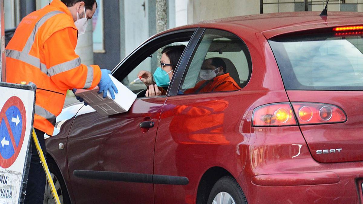 Una vecina de Bueu entrega en As Lagoas un bote con una muestra de saliva para la PCR.   | // G.NÚÑEZ