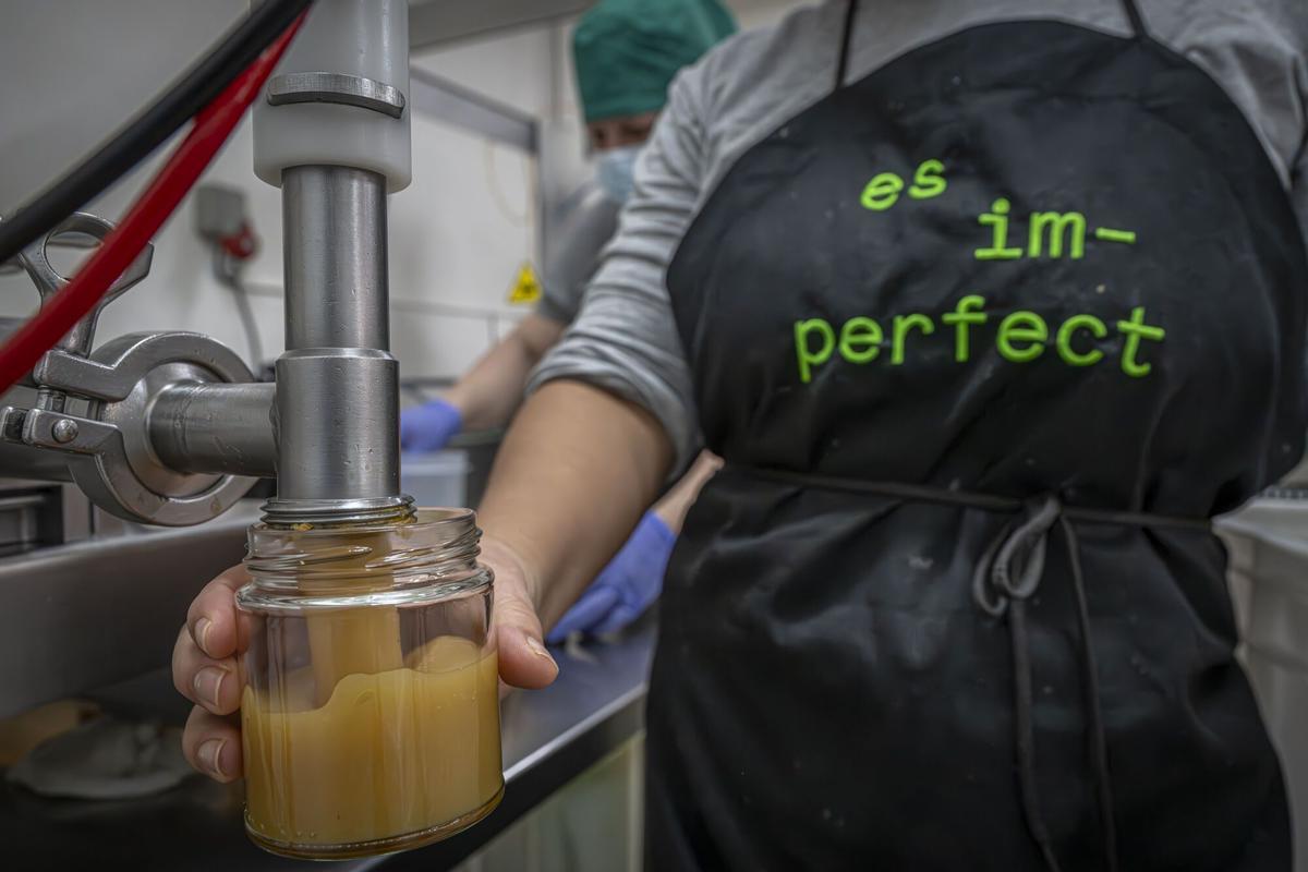 Una trabajadora de És Im-Perfect envasa un bote de compota de manzana, en las antiguas instalaciones de la empresa en El Prat de Llobregat.