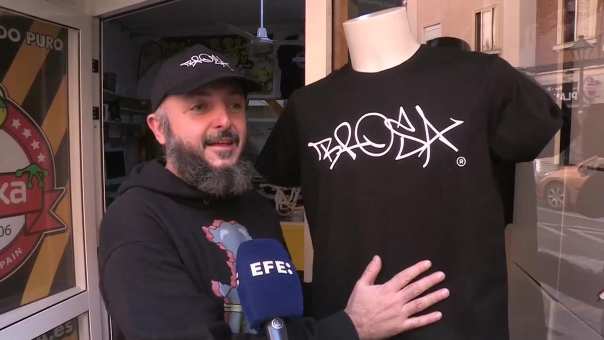 Le pintan un grafiti en su tienda y lo registra y vende camisetas con él.