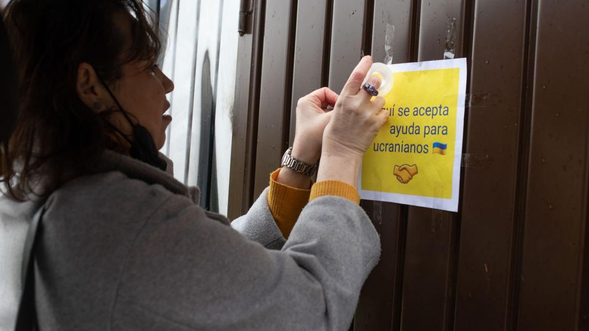 Olena pega un cartel en el que demanda ayuda para sus compatriotas. |