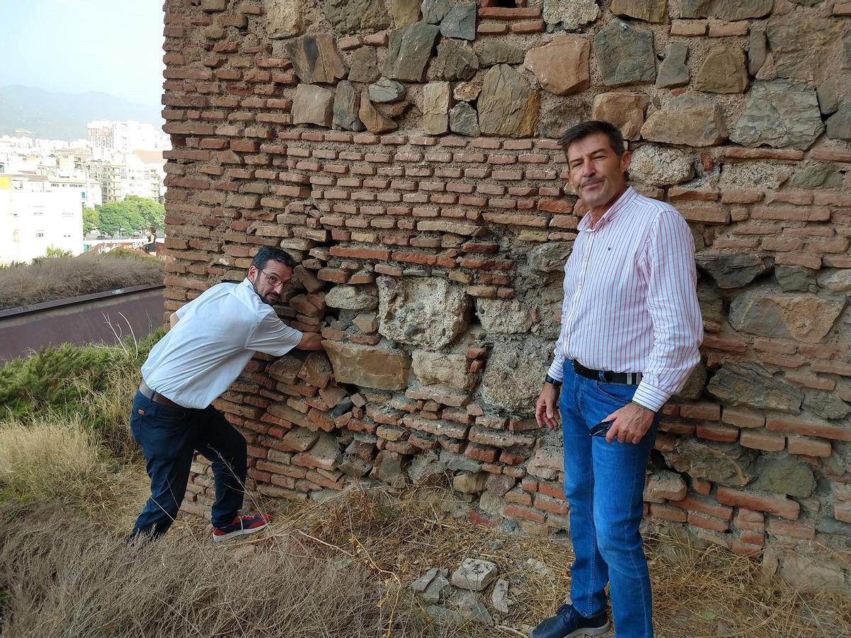 El guía turístico introduce el brazo en la base de la torre dañada.