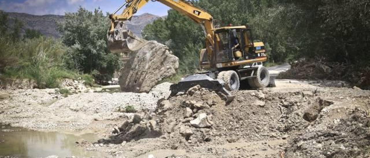 Una máquina excavadora trabajando en la reposición del paso del río Serpis que sirve de acceso a la depuradora de la Font de la Pedra.