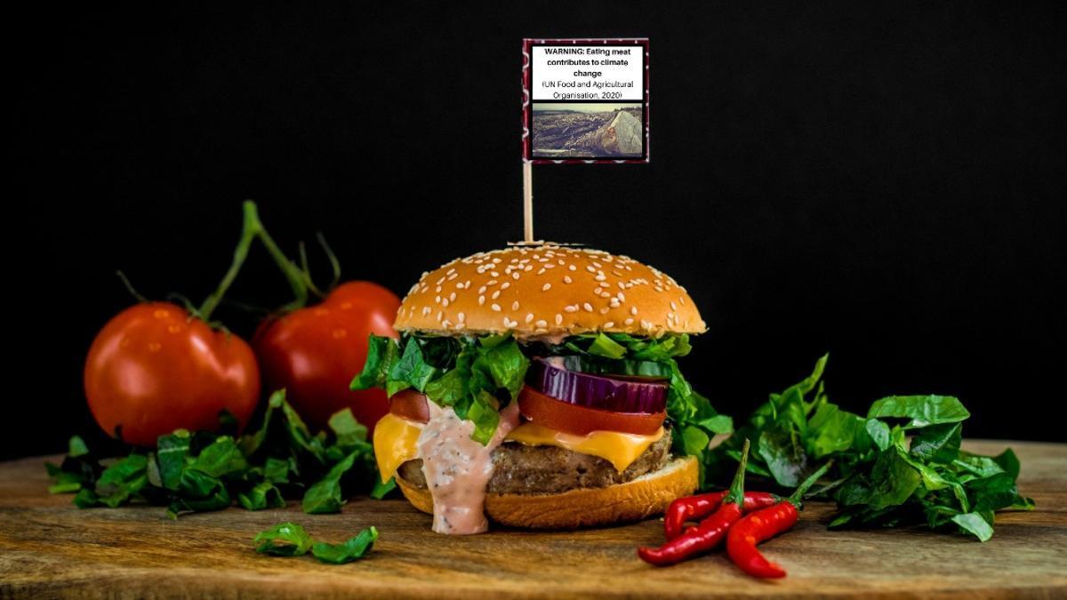 Una hamburguesa con una 'etiqueta' en la que se advierte sobre el impacto de la carne en el medio ambiente.