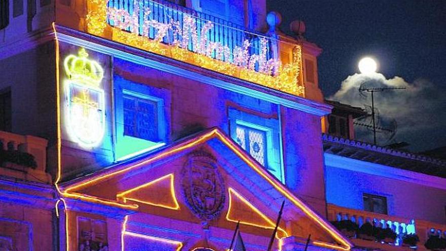 Iluminación de la fachada del Ayuntamiento de Oviedo con la Luna llena sobre una nube a  la derecha. En la imagen siguiente, iglesia de San Isidoro y mercado del Fontán, al anochecer.