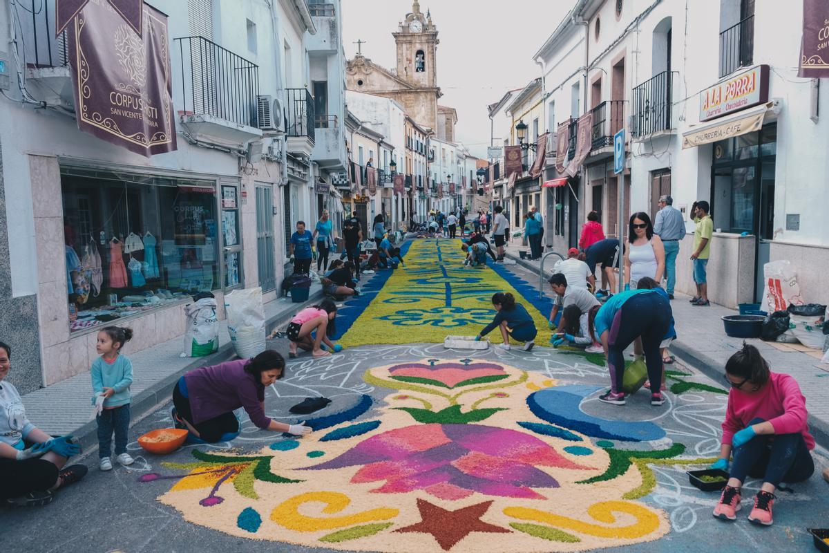 Los devotas realizan la alfombra de arte efímero por las calles de San Vicente de Alcántara.