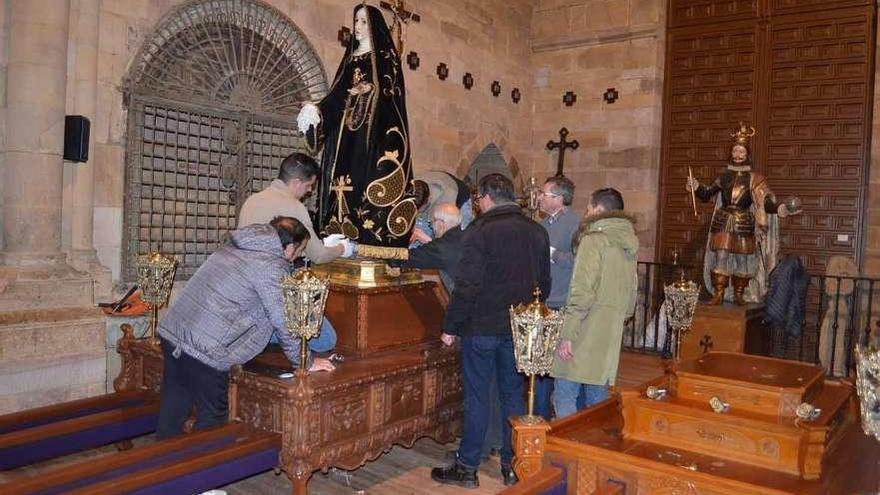 Varios cofrades nazarenos en los preparativos de la Virgen para la procesión del Encuentro.