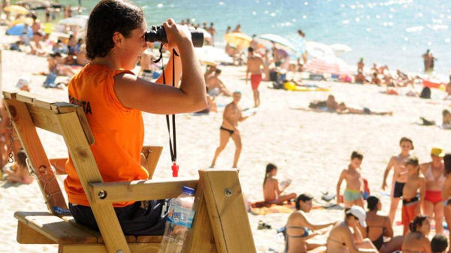 Una socorrista vigila a los bañistas en una playa gallega.  // G. Santos