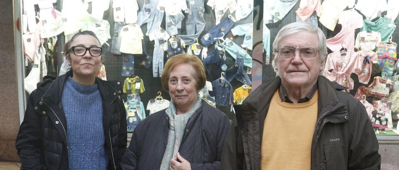 Mónica Estévez, junto a
sus padres, Adelaida y Carlos,
 frente a la tienda familiar
en activo.  // R. Grobas