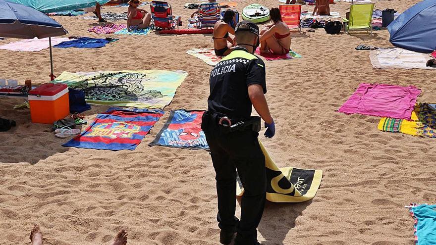 Un policia retira un tovallola de la platja de Tamariu, ahir.