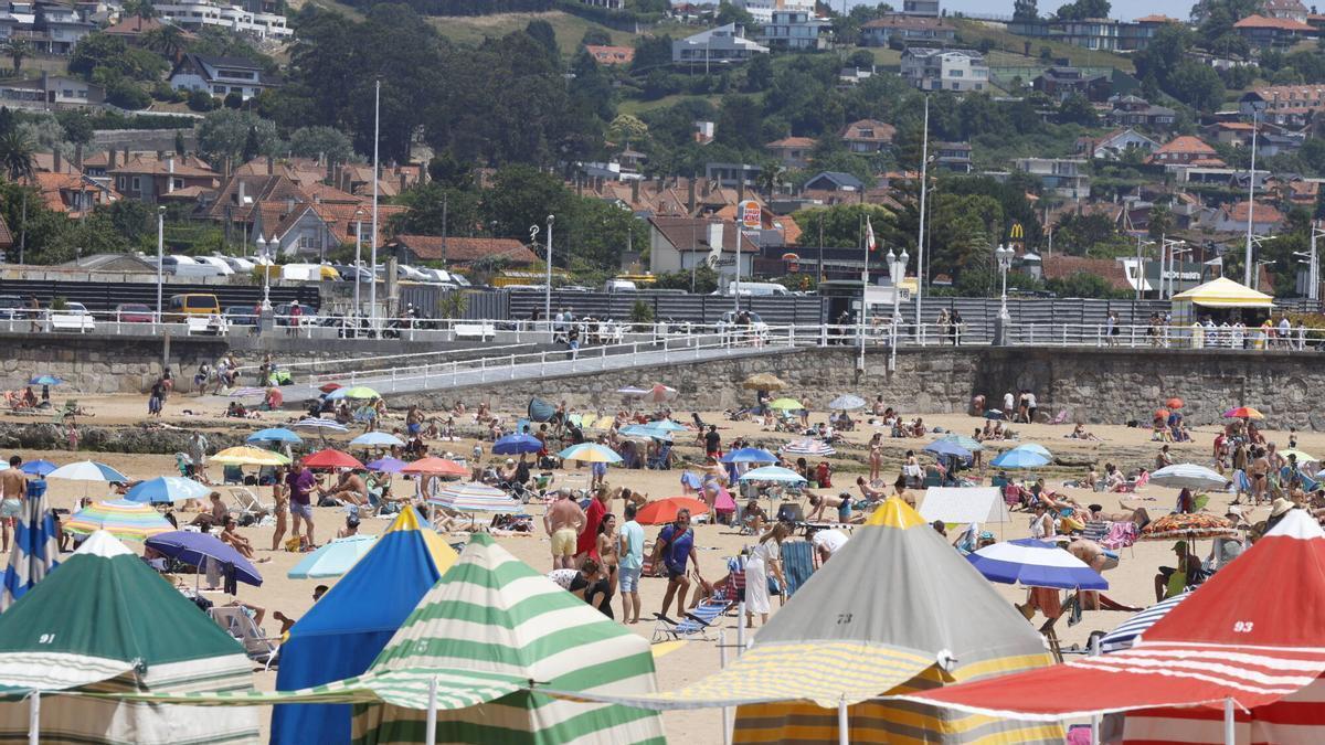 Ciudadanos disfrutando del calor y refrescándose en las duchas de la playa de San Lorenzo
