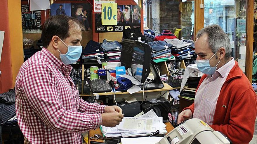 José Yanes atiende a Ramón López en su tienda de Vegadeo.