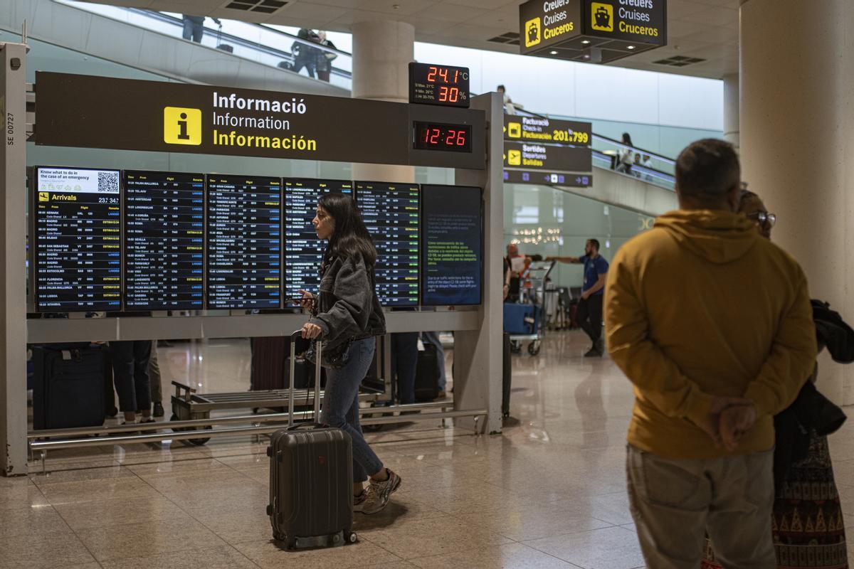 Varias personas observan un panel de llegadas en el aeropuerto de Barcelona, en una imagen de archivo.