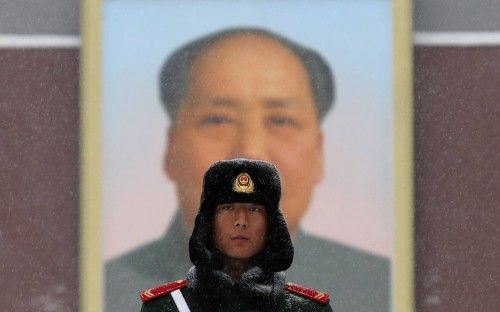 A paramilitary policeman stands guard in front of the giant portrait of late Chinese Chairman Mao at the main entrance of the Forbidden City in the snow in Beijing
