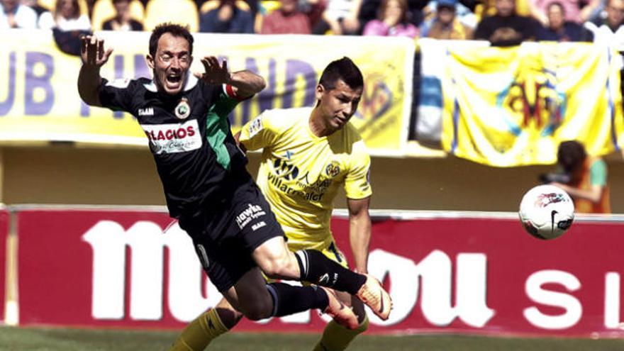 El delantero del Racing de Santander Pedro Munitis (i) cae ante el centrocampista paraguayo del Villarreal CF Hernán Pérez.