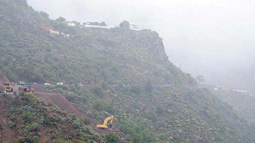 Operarios trabajando, ayer, en la carretera de Tejeda, con una fuerte neblina asomando al fondo.  MARRERO