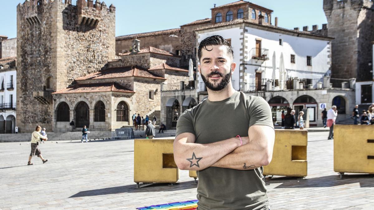 Jorge Peralta en la plaza Mayor de Cáceres, con la bandera del colectivo LGTBI al fondo.