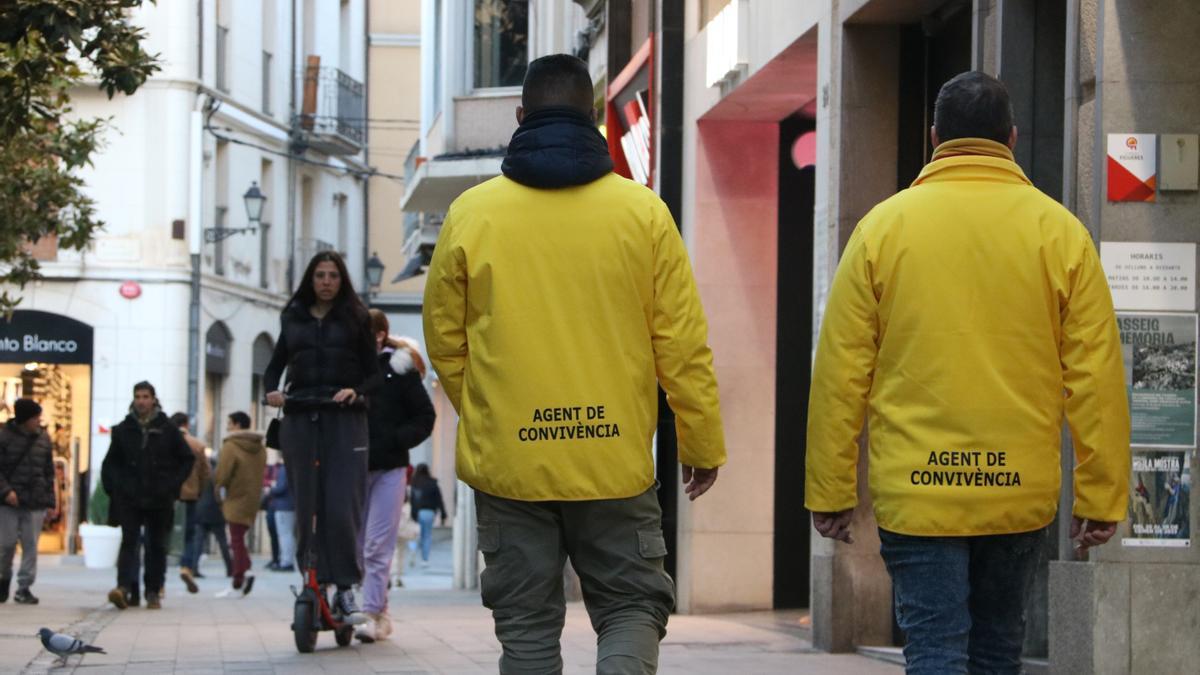 Dos agents de convivència amb una noia amb patinet al fons.