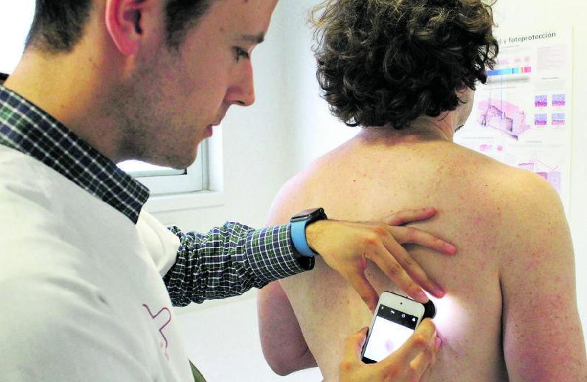 El doctor Javier Ruiz revisa la piel a un paciente en la consulta.