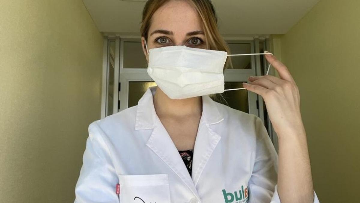 Una sanitaria, poniéndose una mascarilla.