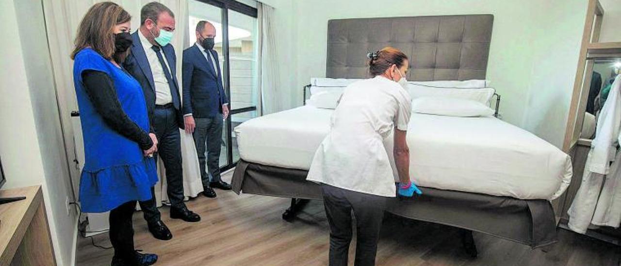 Una ‘kelly’ manipula una cama elevable, obligatorias con la nueva ley, ante la mirada de Francina Armengol y Gabriel Escarrer.