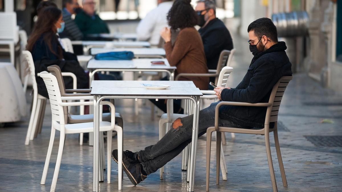 Un hombre con mascarilla en una terraza.