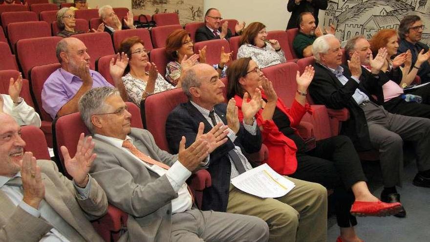 El público asistente y, en detalle, Menéndez, durante su conferencia, muestra un ejemplo de cristal que capta la luz y la convierte electricidad.