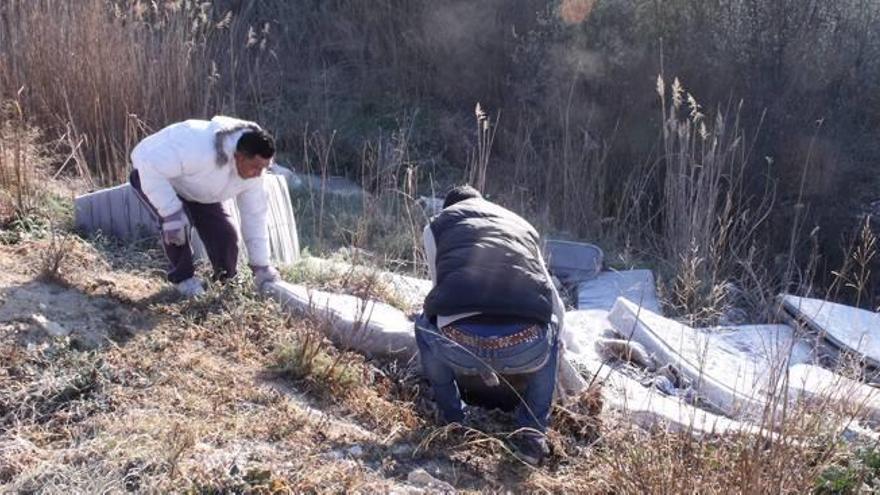 Voluntarios trabajando en la retirada de colchones abandonados; a la derecha, algunos participantes con las bolsas repletas de basura recogida.