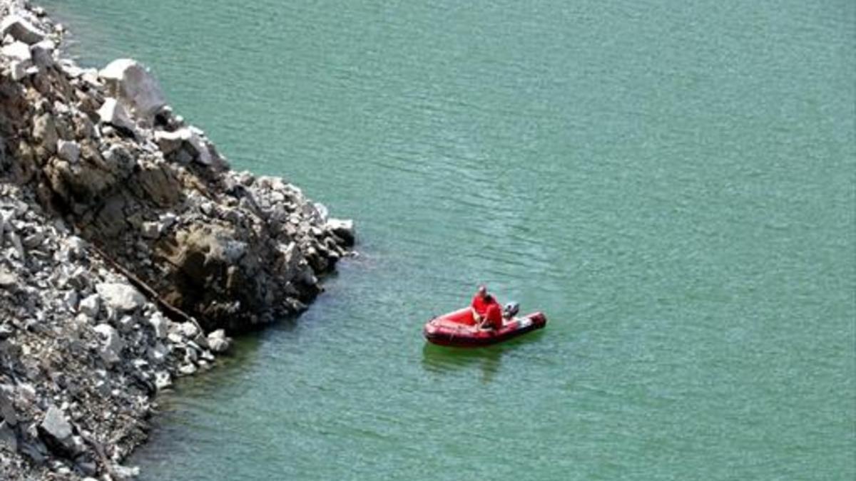 Una embarcación rastrea el perímetro del pantano de Susqueda, ayer.