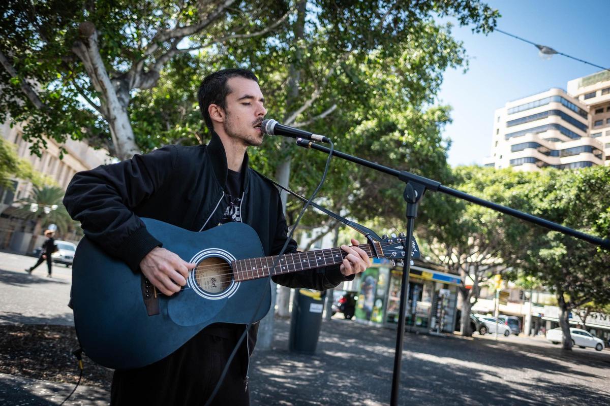 Un músico callejero toca la guitarra y canta en la plaza de España, en el municipio de Santa Cruz de Tenerife.