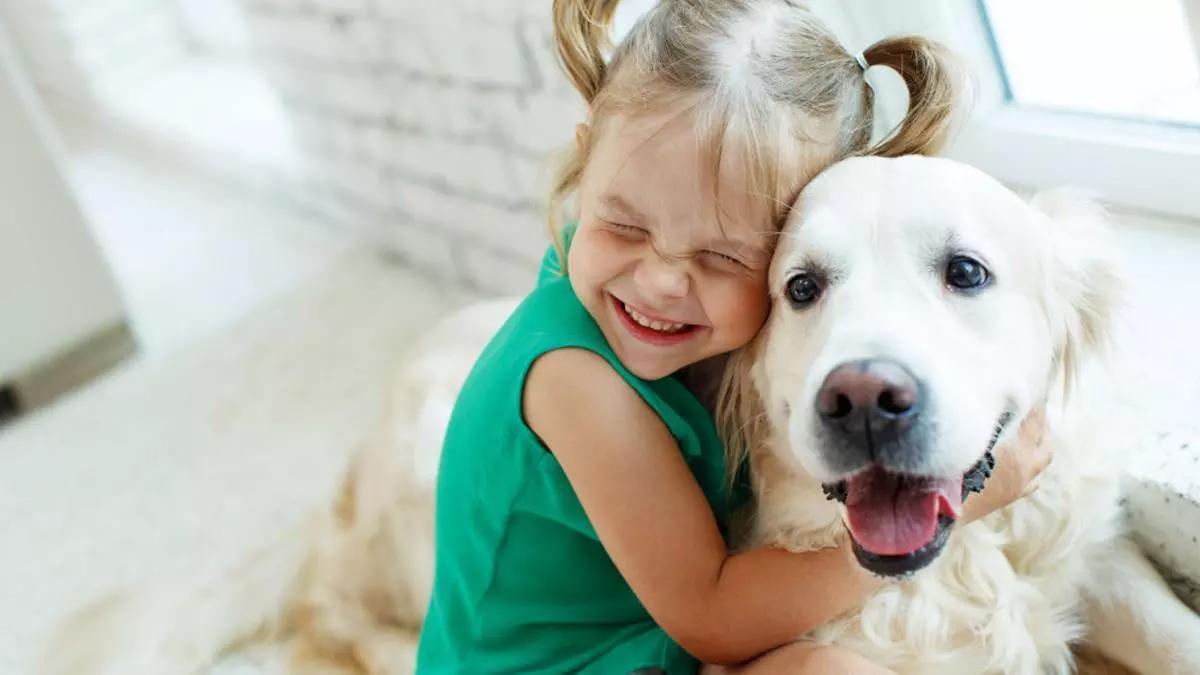 Una niña abraza a un perro.