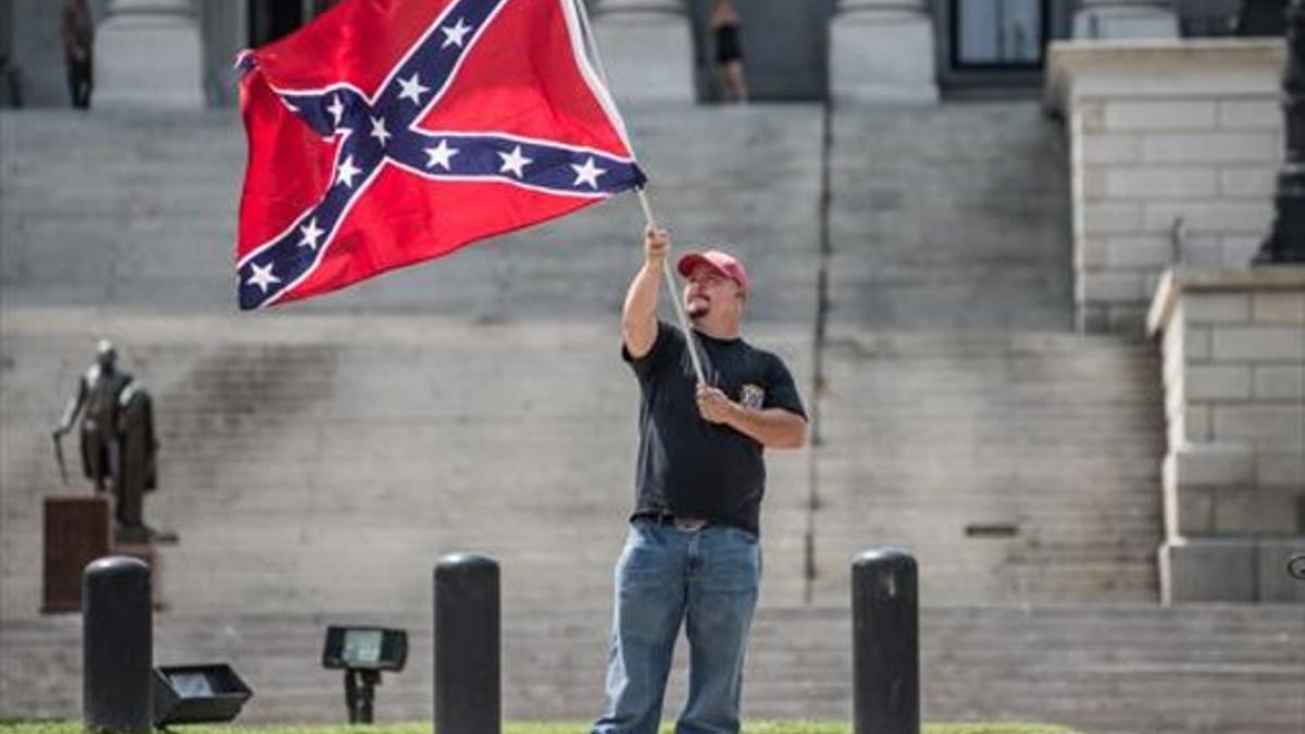 Un hombre ondea la bandera confederada frente al Capitolio.