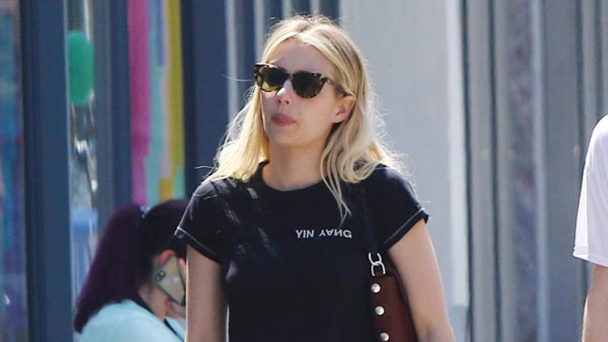 El look de Emma Roberts con pantalones vaqueros negros, sandalias planas, camiseta básica y bolso marrón