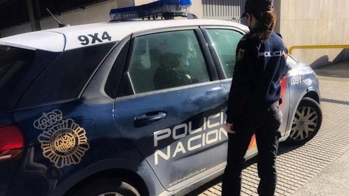 Una agente de la Policía Nacional junto a un coche patrulla.