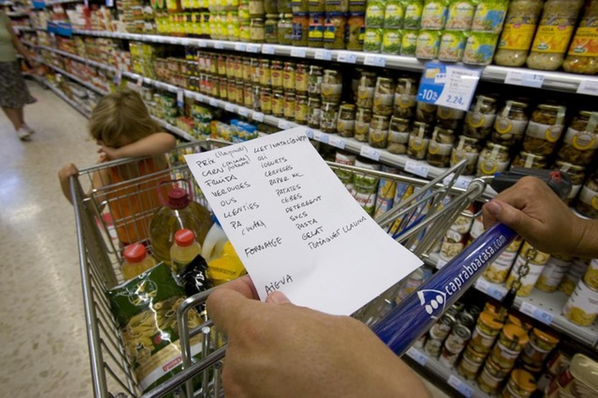 Una mujer repasa la lista de la compra, en un supermercado.